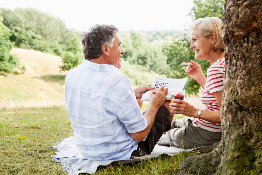 Mature couple sitting in the park doing a crossword