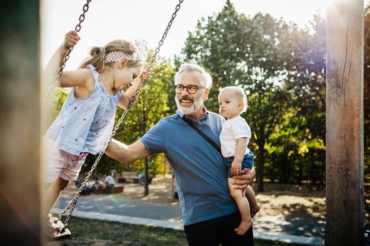 Grandfather plays with grandchildren on the swings