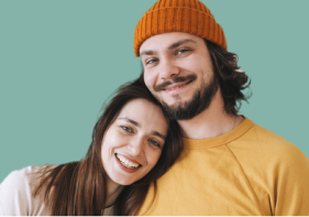 Smiling couple in their mid-thirties on a teal green background