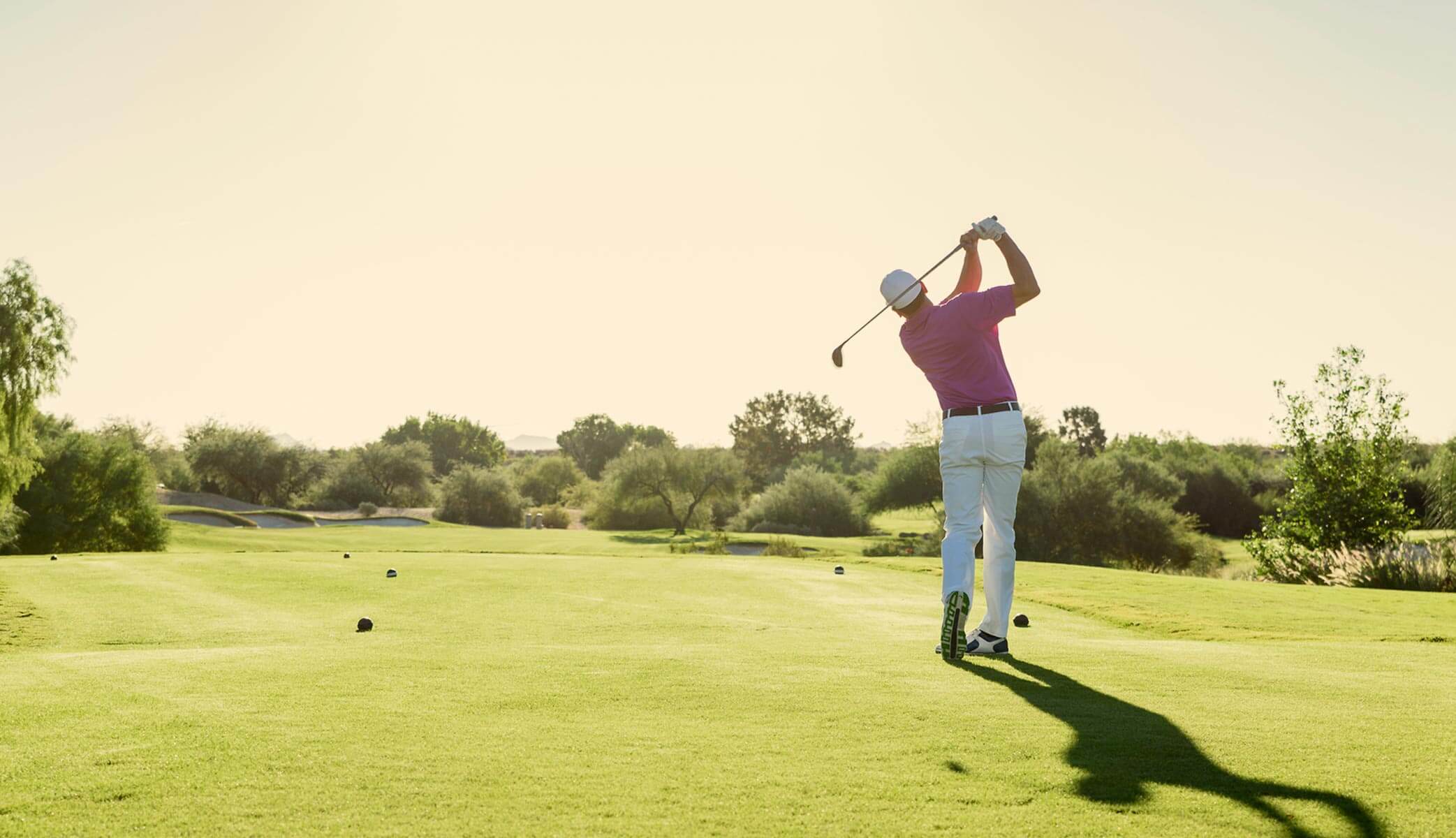 Man swinging a golf club on a beautiful course